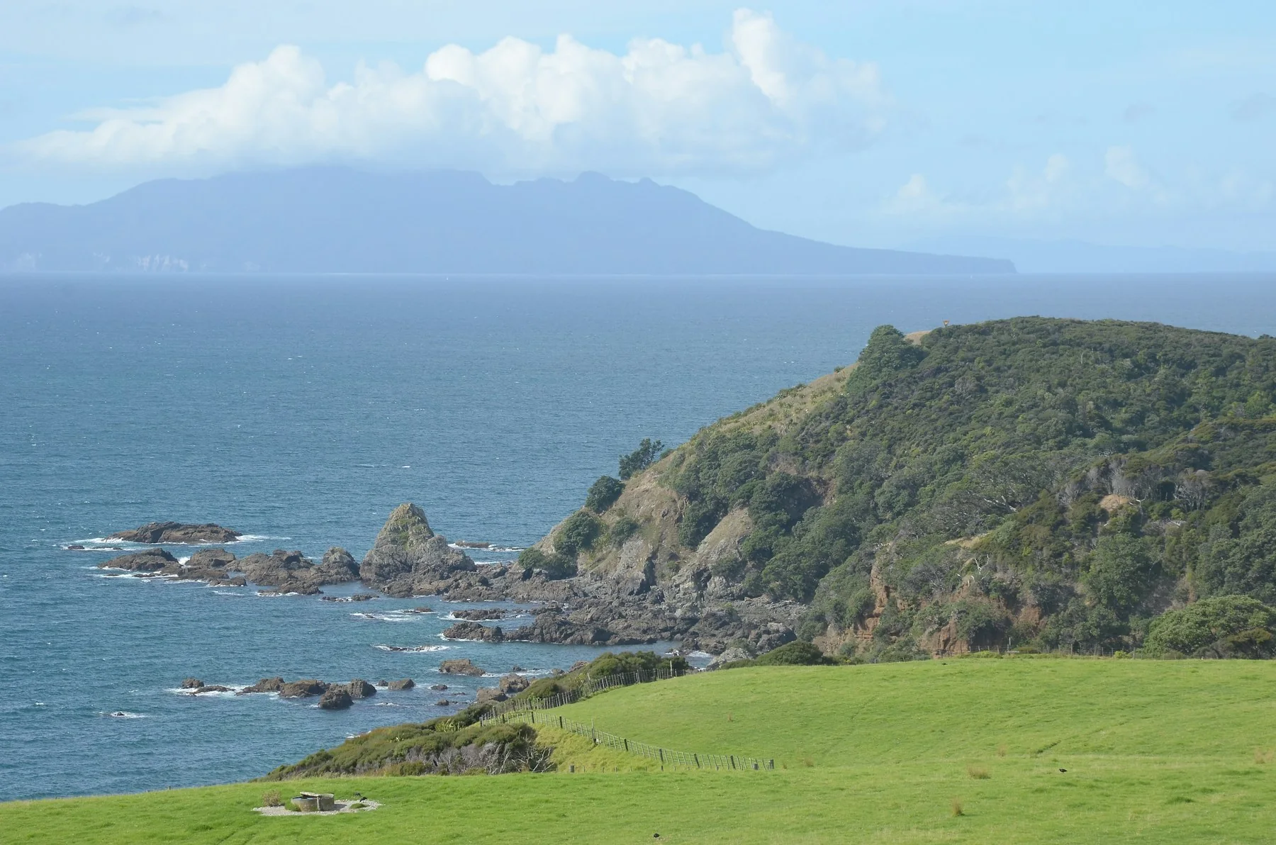 Green coastal hills meeting a quiet blue sea